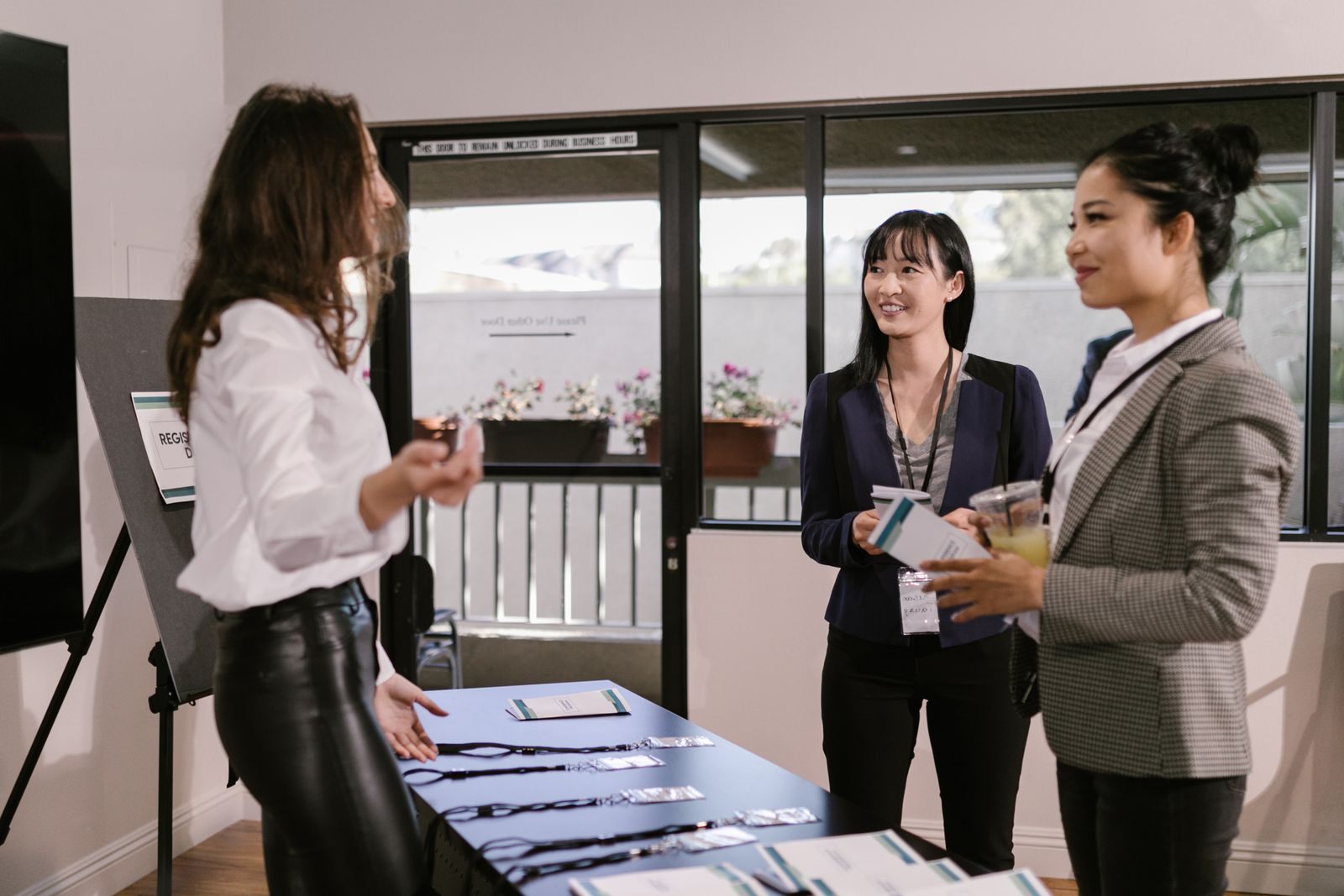 Three women at a registration table with brochures at a business event, a simple setup for travel expo booth ideas