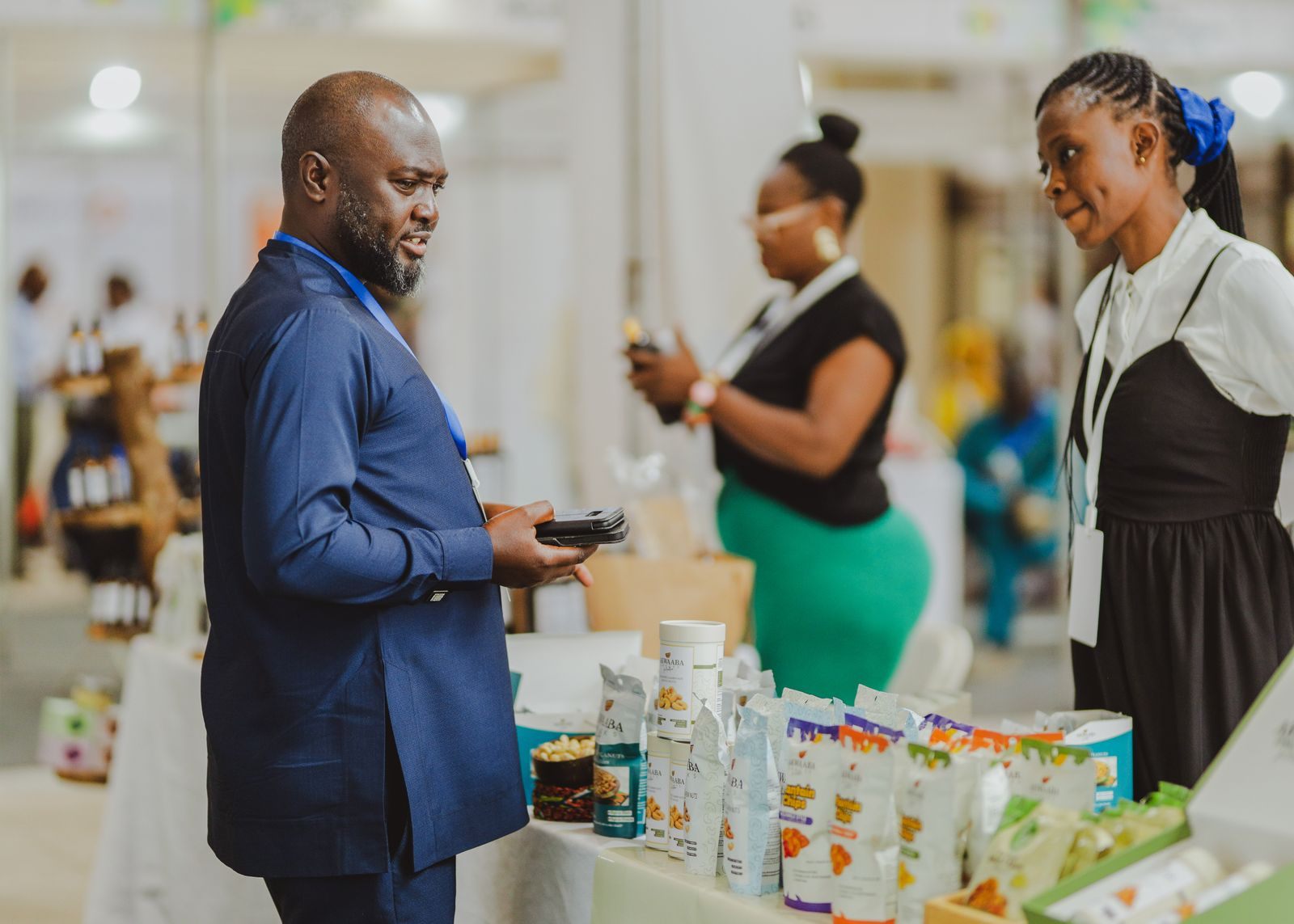 An exhibitor in a suit talks with two visitors at a busy stand: the selling side of travel trade shows