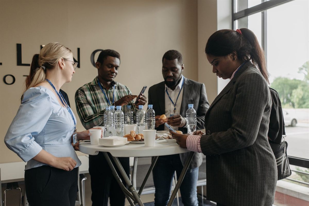 Delegates with name badges chatting around a standing table at a conference break