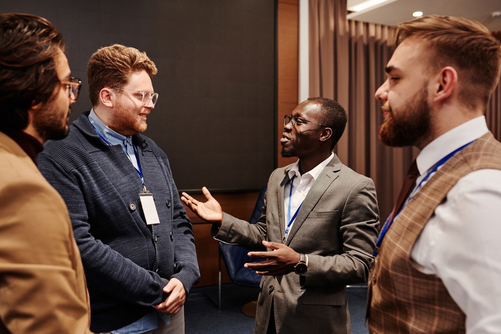 Four men with lanyards talking in a group at a business event, the heart of travel agent networking events