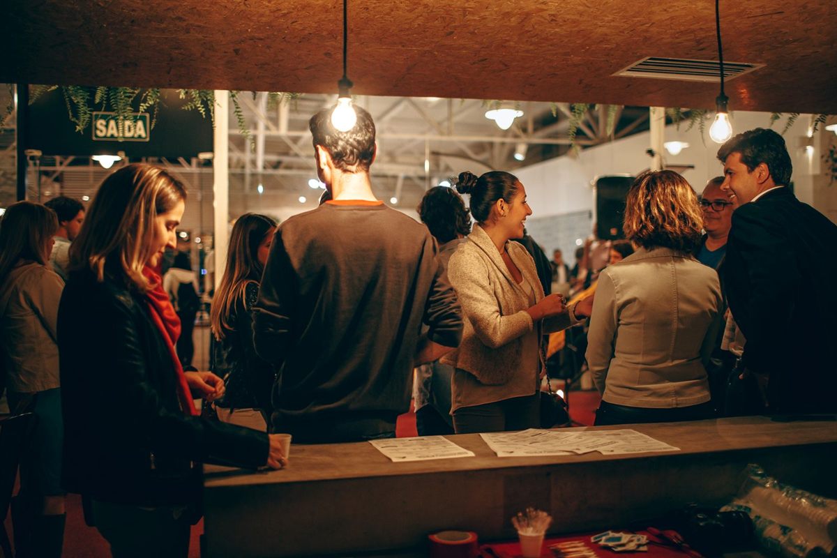 Visitors gathered at a counter under hanging lights in a busy event hall